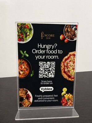 Une affiche promotionnelle présentant le service en chambre de l’hôtel Encore Inn, avec un code QR permettant de commander des plats.