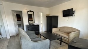 A living room with a sofa, a coffee table, a TV, and a cabinet. - Encore Inn Inglewood  (Inglewood)