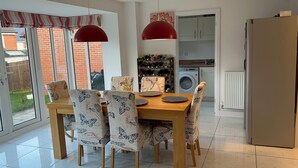 A dining area with a wooden table and butterfly-patterned chairs, a red pendant light, and a wine rack in the background.