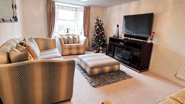 A living room with a sofa, ottoman, and a television.