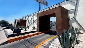 L’entrée d’un motel, avec une enseigne bien visible, une architecture moderne et un espace paysager agrémenté de cactus.