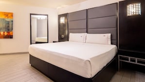 Une chambre à coucher moderne avec un grand lit, une tête de lit sombre et un plancher de couleur claire.