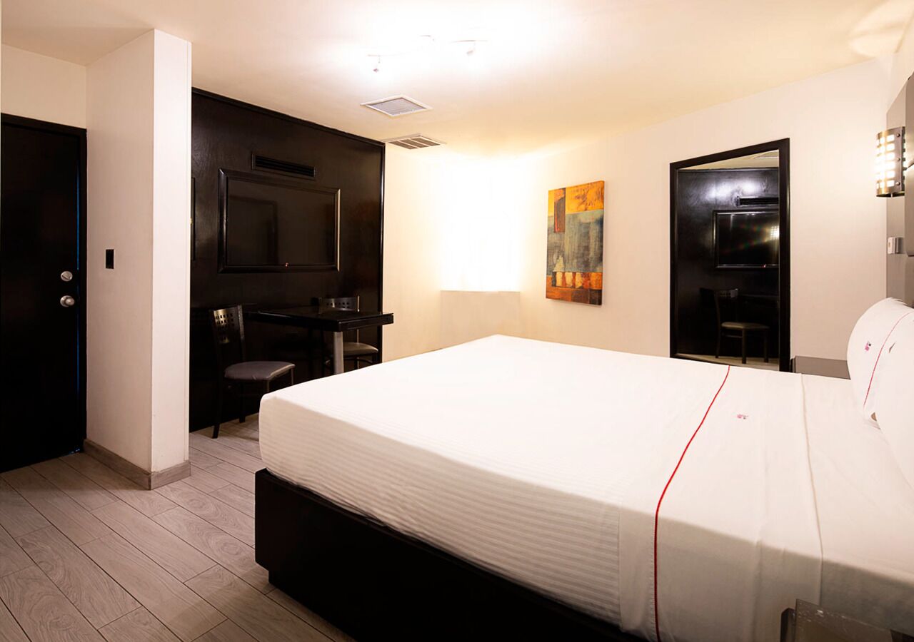 Una camera d'albergo con un letto grande, una scrivania con una sedia, un armadio e un quadro appeso al muro.
