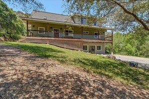 A two-story house with a balcony, a covered porch, and a gravel driveway. - Comfort in Nature, Multi-Family, Sleeps 14, BBQ (Three Rivers)