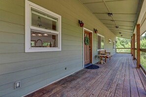 A covered porch with a wooden floor, a bench, and a door with a wreath. - Comfort in Nature, Multi-Family, Sleeps 14, BBQ (Three Rivers)