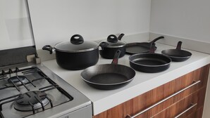 A kitchen with a gas stove, black pots and pans, and wooden cabinets. - Apartment in Sonata, Puebla (Heroica Puebla de Zaragoza)