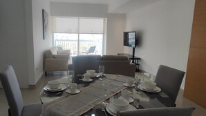 A dining area with a table set for four, a sofa, and a TV on a stand. - Apartment in Sonata, Puebla (Heroica Puebla de Zaragoza)