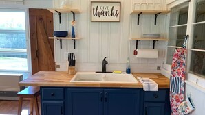Una cucina con mobili blu, un piano di lavoro in legno e un cartello con la scritta 'GIVE thanks'.