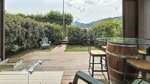 An outdoor patio with a wooden table and chairs, a glass-top table, and a barrel. - Brison-Saint-Innocent - L'Instant paisible (Brison-Saint-Innocent)