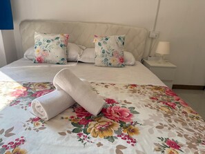 A neatly made bed with floral bedding, two matching pillows, and a rolled towel on the bed. - RAHIMA GUEST HOUSE (Rome)
