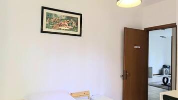 Una habitación de hotel con una cama, una mesita de noche, una lámpara y una puerta que da al baño.