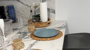 Una encimera de mármol con dos platos azules, un dispensador de servilletas de papel blanco y un mantel tejido.