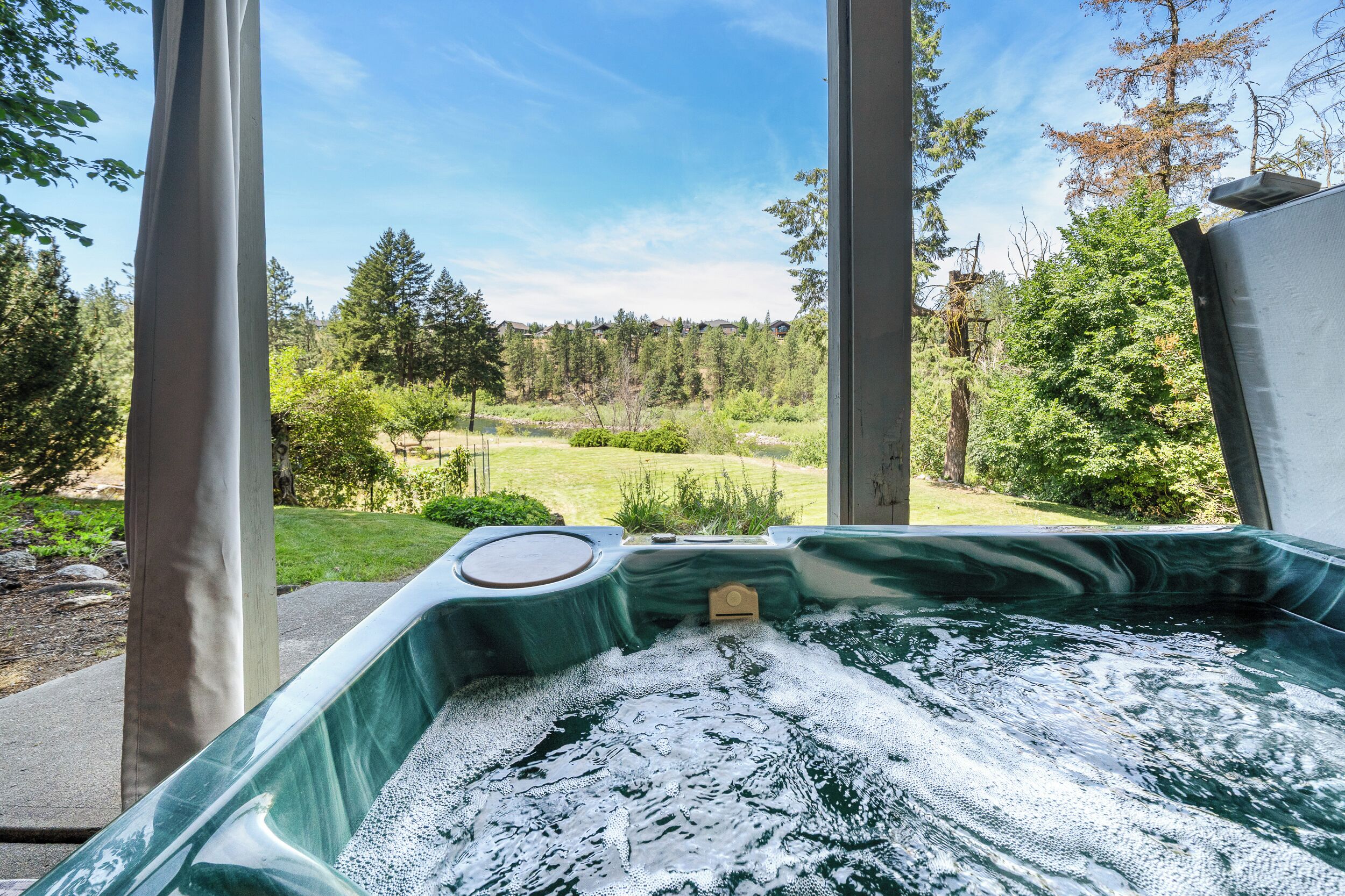 A hot tub with a view of a forest and a grassy area.