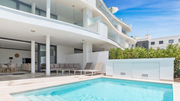 Et moderne hus med swimmingpool, spiseområde og stue med sofa og stole.