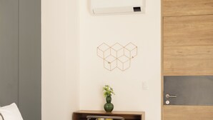 Et soveværelse med en seng, et skrivebord med stol, en vægmonteret aircondition og en trædør.