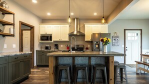Una cucina moderna con isola centrale, sgabelli da bar e mobili in legno.