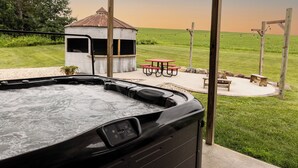 A hot tub, a gazebo, and picnic tables in a grassy outdoor area.