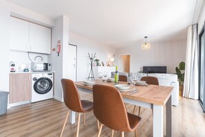 Une cuisine moderne équipée d’un lave-linge, d’une table à manger, de chaises et d’un téléviseur dans l’espace de vie.