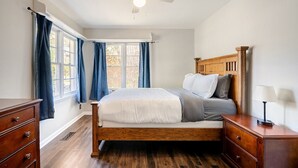A bedroom with a wooden bed, a nightstand, a dresser, a ceiling fan, and a window with curtains. - Magnolia - 4 Bedroom 2 bath & pets allowed (Norman)