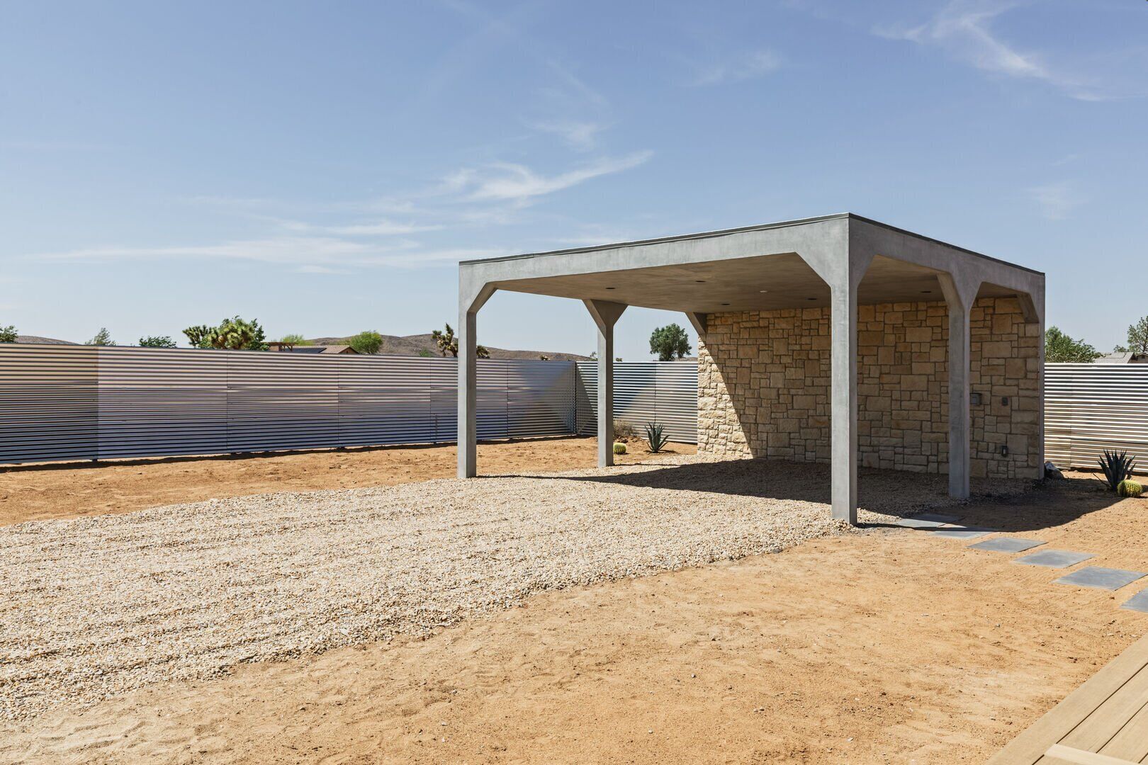 A covered outdoor area with a stone wall and metal fence.