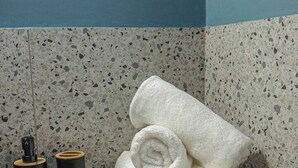 A bathroom with a speckled tile backsplash, a towel rack, and two black dispensers on the counter. - Aelia Sky View Loft & Rooftop Acropolis View (Athens)