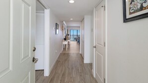 A hallway with white doors, a wooden floor, and a framed abstract painting on the wall.