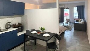 A compact living space with a kitchenette, dining area, and a seating area with a sofa and a chair. - Aelia Loft with Terrace & Rooftop Acropolis View (Athens)