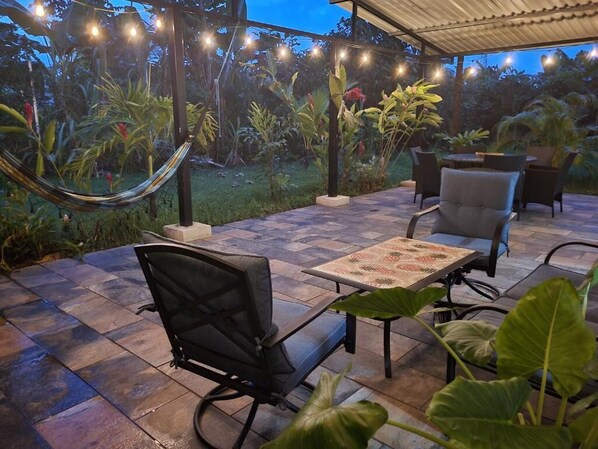 An outdoor patio with a hammock, chairs, and a table.