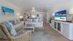 Un salón amplio con un sofá blanco, una mesa de centro y un televisor sobre un mueble.