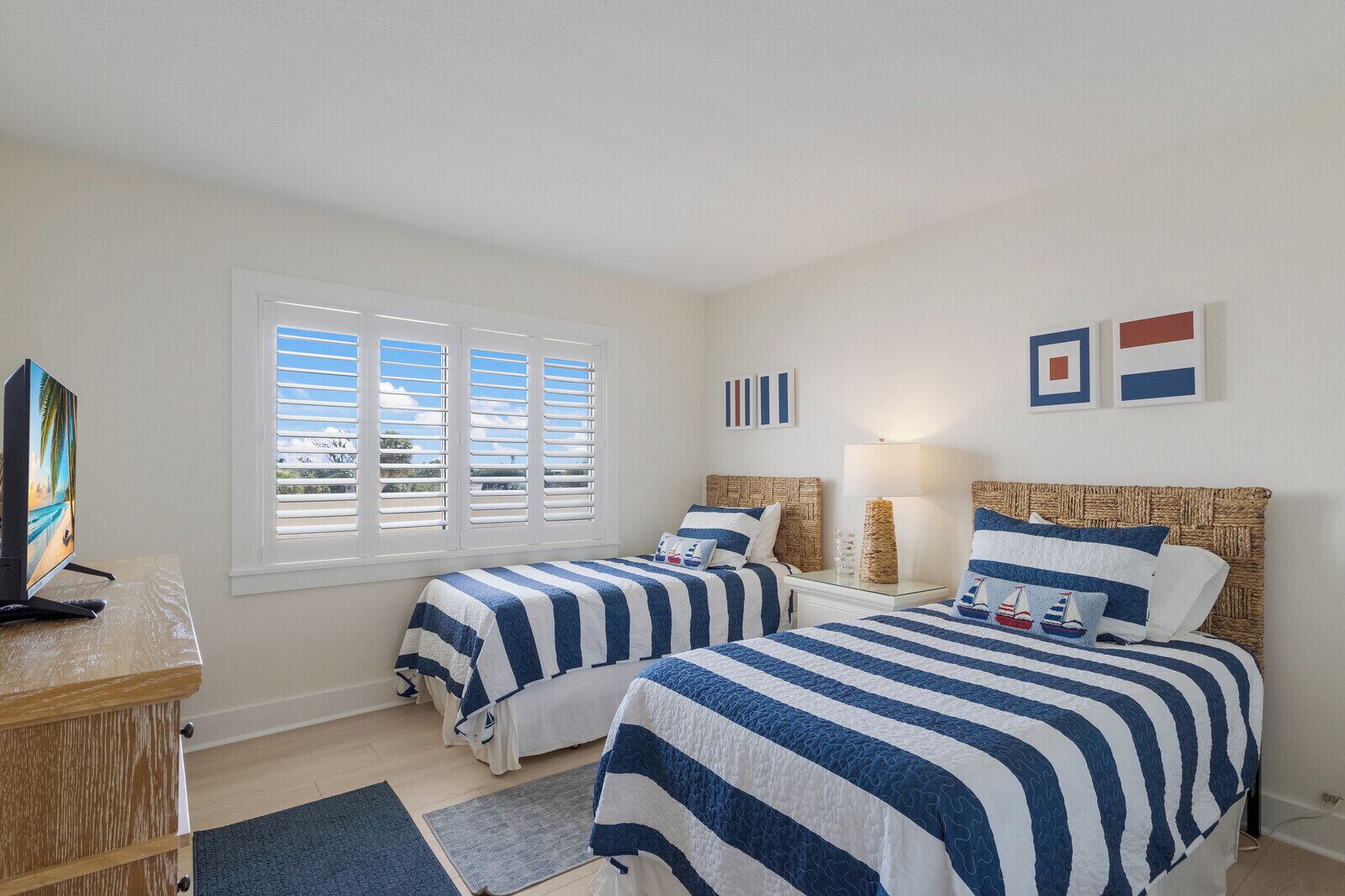 A hotel room with two beds, a TV, and a window with blinds.
