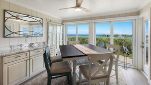 A kitchen with a view of the ocean, a dining table, and chairs.