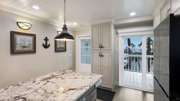 A kitchen with a marble countertop, pendant lighting, and a view to a balcony with outdoor scenery.