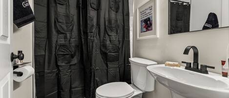 A bathroom with a white toilet, a sink, and a shower curtain with pockets.
