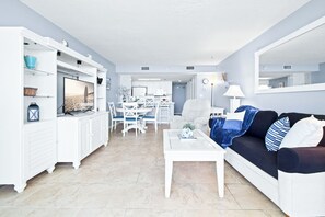 Una sala de estar moderna con un sofá blanco, una mesa de centro y un comedor con sillas y una mesa blancos.