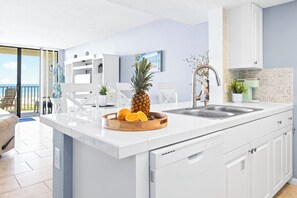 A modern kitchen with a large island, white cabinetry, and a view to the outside.