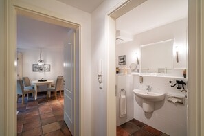 Ein Hotelbad mit Waschbecken, Spiegel, Handtuchhalter und einem kleinen Tisch mit Stühlen.