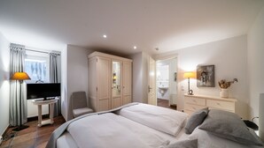 A hotel room with a bed, a TV, a desk, and a wardrobe. - Souterrain Ferienwohnung in Dierhagen (Ostseebad Dierhagen)