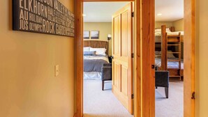 A hallway leading to a bedroom with a bed, a nightstand, and a wall-mounted light.