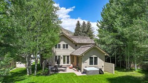 A two-story house with a patio, a covered outdoor seating area, and a small attached garage.
