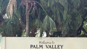Señal de bienvenida a Palm Valley, fundada en 1968, con palmeras y pequeñas plantas de palma al frente.