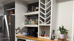 Una cocina con estante para vinos empotrado, estación de café y refrigerador de acero inoxidable.