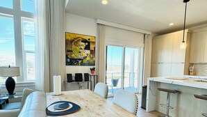 A modern kitchen with a large island, a dining area with a wooden table, and a view of the outdoors. - NEW Modern 3 bed Home with Stunning Mountain Views close to Ski Resort and City (Sandy)