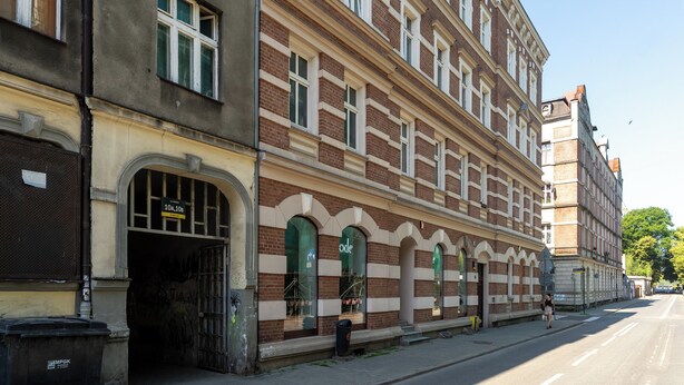 A historic building with a large arched entrance, a visible address sign, and a street view. - Silesian Charm Kozielska 1 Studio (Katowice)
