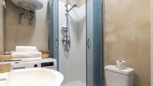 Ein Badezimmer mit Dusche, Toilette, Waschbecken und einer Waschmaschine.