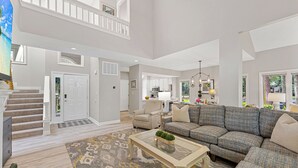 A spacious living room with a high ceiling, a staircase, a sofa set, and a dining area. - Family Villa | Deck, Lagoon Views, Complex Pool, Bikes (Hilton Head Island)