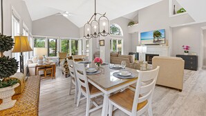 A spacious living area with a dining table, chairs, a sofa, and a television. - Family Villa | Deck, Lagoon Views, Complex Pool, Bikes (Hilton Head Island)