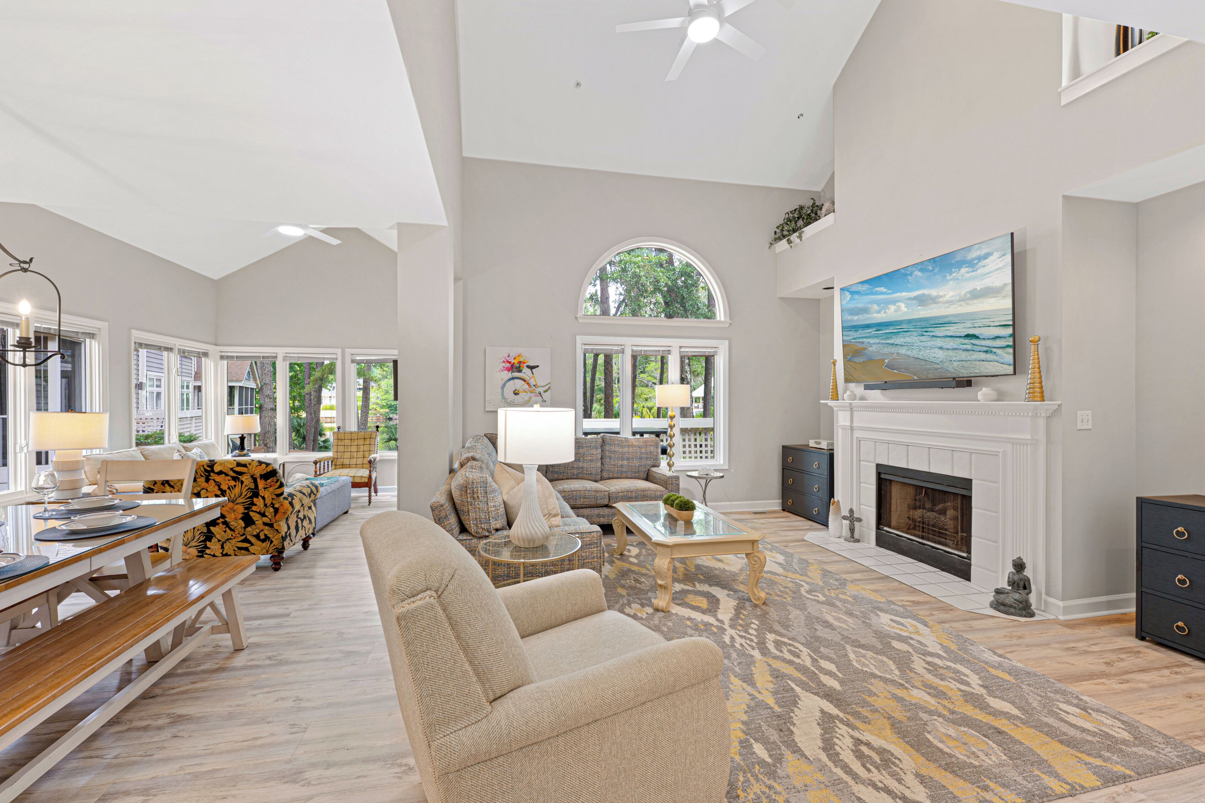 A spacious living room with a fireplace, a large TV, and a dining area with a bench and table.