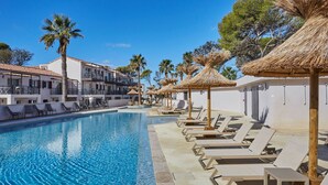 Une piscine avec des chaises longues et des palmiers.
