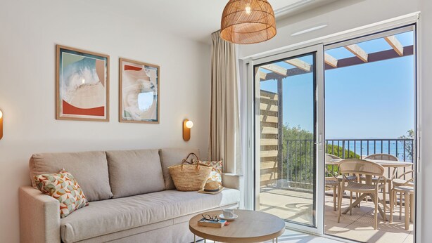 Un salon moderne avec un canapé, une table basse ronde et une vue sur le balcon extérieur.
