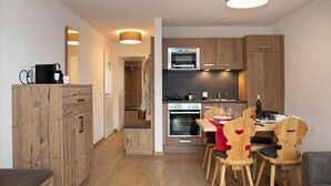 A modern kitchen with wooden cabinets, a dining area with a red tablecloth, and a cozy seating area.